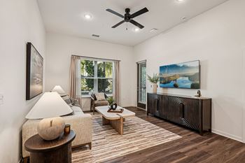 A living room with a ceiling fan and a painting of a lake
